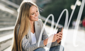 woman sits on steps outside and reads about dentures on her phone