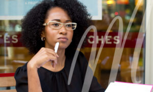 woman in glasses holds pen to her face while learning about implants and other common myths