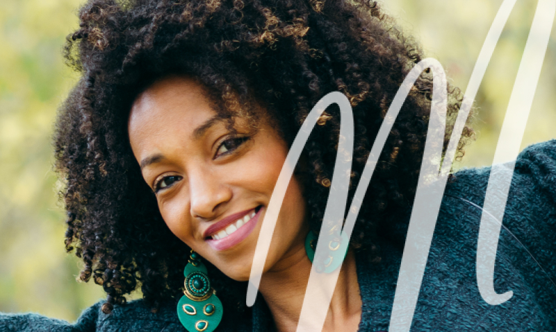 woman in blue top and teal earrings smiling